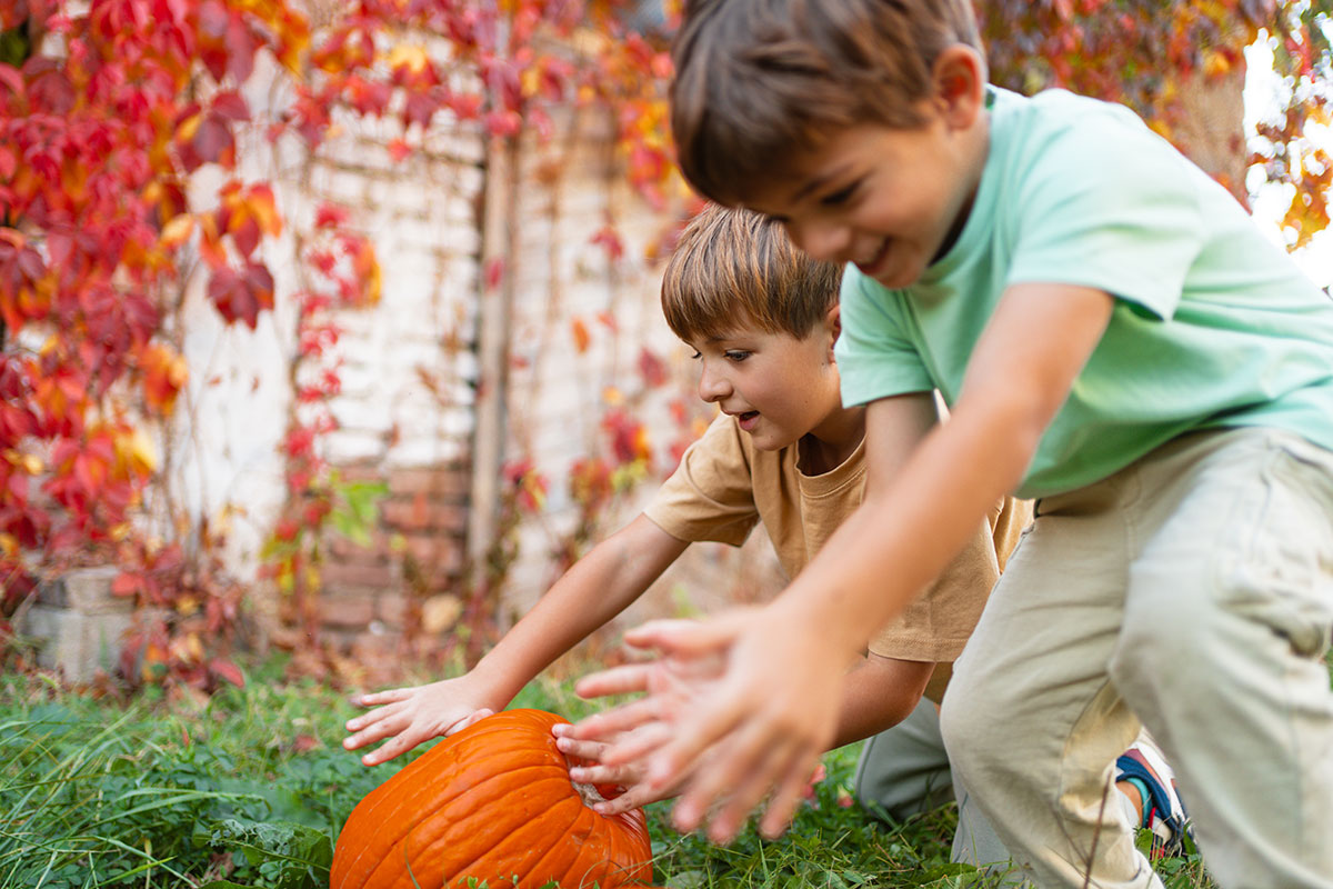 Children playing with a pumpkin outdoors in autumn