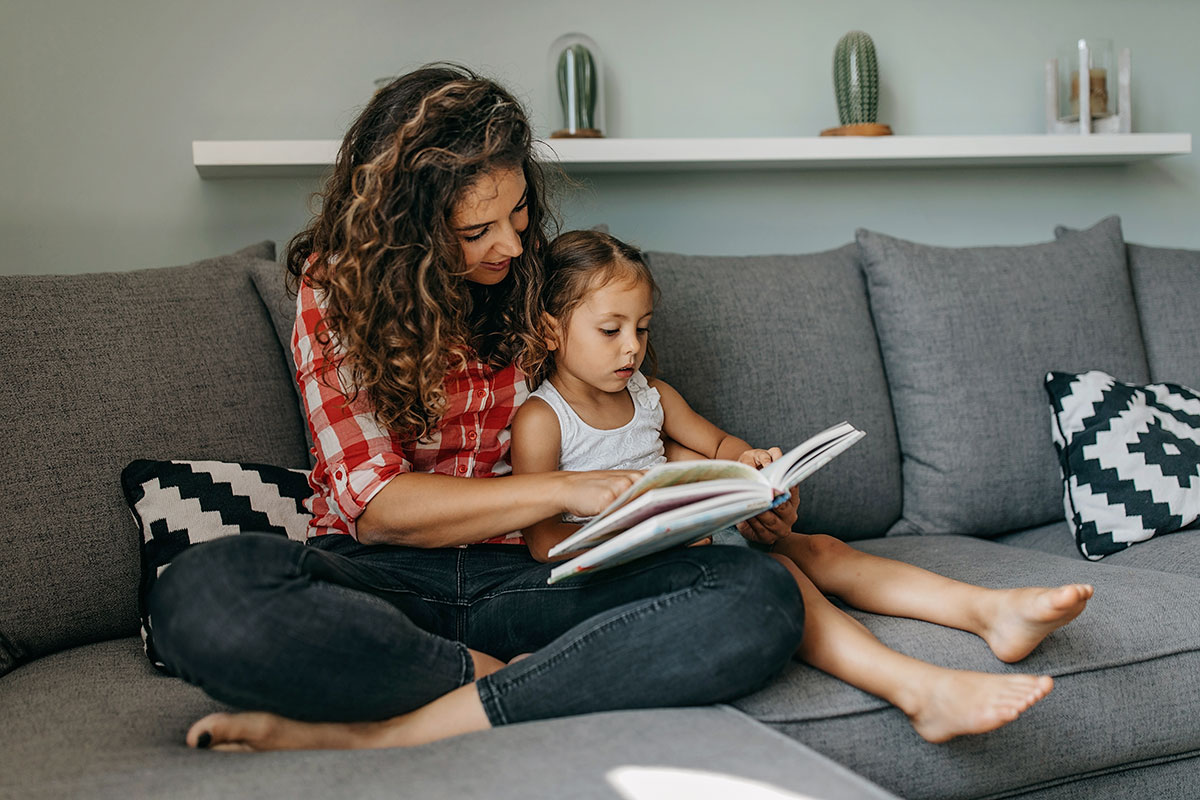 Woman reading a book with child on couch