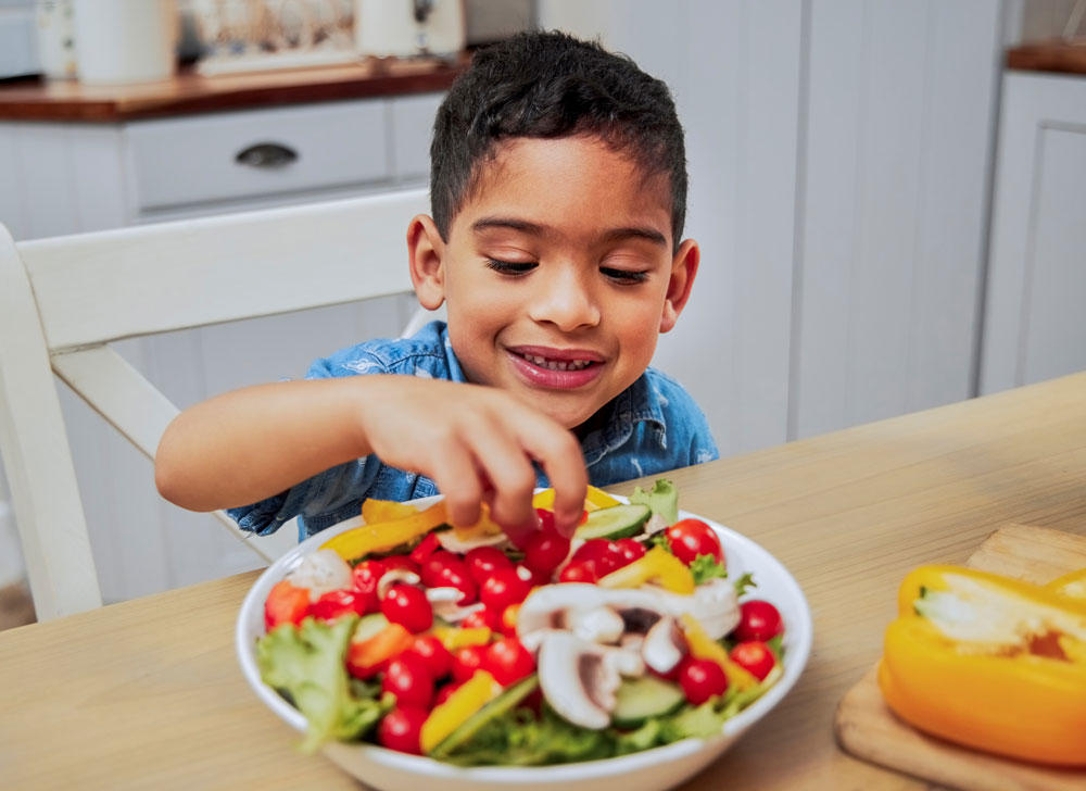 Boy eating a colorful vegetable salad