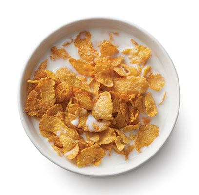 Bowl of cornflakes with milk, top view.
