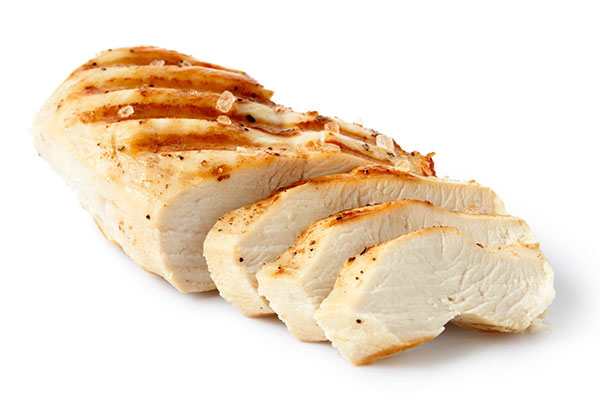 Sliced grilled chicken breast on white background.