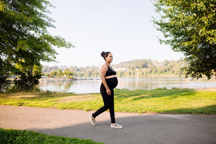 Pregnant woman walking by a scenic lakeside path.