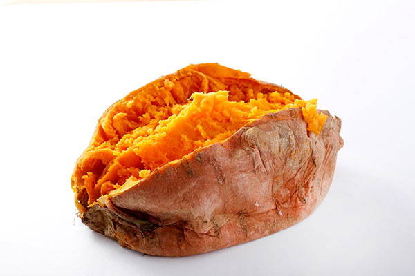 Baked sweet potato with orange flesh exposed.