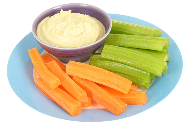 Carrot, celery sticks with hummus on plate.